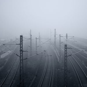 Railway tracks in foggy weather against sky