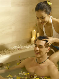 Girlfriend giving head massage to boyfriend in bathtub