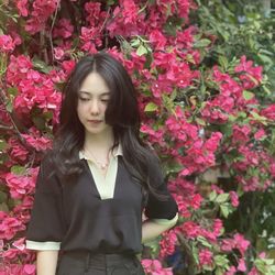 Portrait of young woman standing against yellow flowers