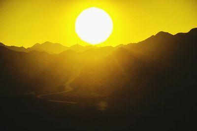 Sun shining through clouds over mountains
