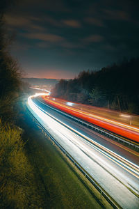 Light trails on road against sky at night