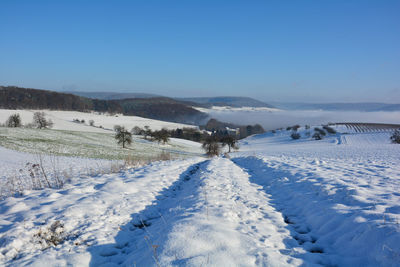 Winter landscape with fields and fog in the valley, with snow, blue sky, germany, bavaria, spessart