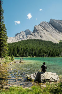 Man sitting on a rock by a lake on a sunny summer day