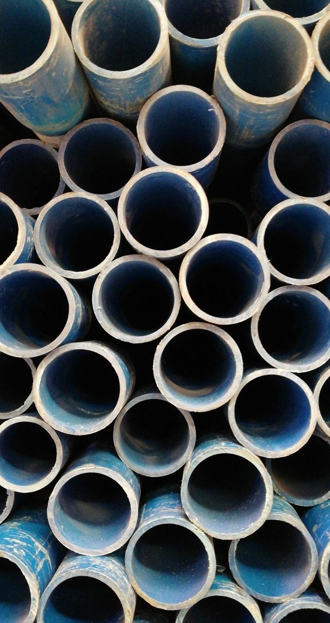 FULL FRAME SHOT OF STACK OF PIPES AGAINST THE WALL