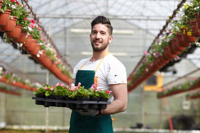 Young man smiling while standing in greenhouse