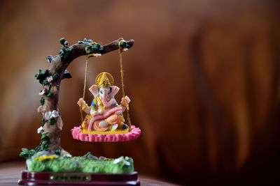 Close-up of figurine on table. hindu god ganesha in art form sitting on a swing. 