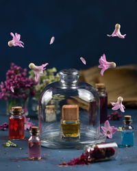 Digital composite image of flowers in mid-air with perfume bottles on table