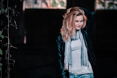 Portrait of beautiful woman standing against black background