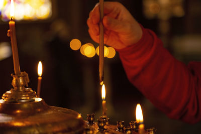 Midsection of man holding illuminated candles in temple