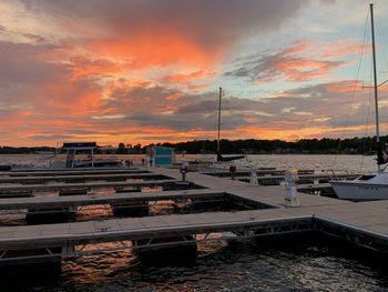 Boats moored in city against dramatic sky during sunset