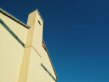 Low angle view of smoke stack against clear blue sky