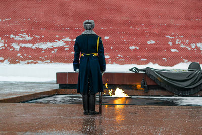 Rear view of security guard standing on street during winter