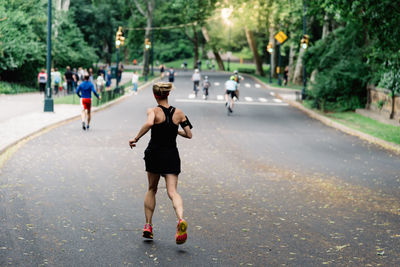 Rear view of people running on road