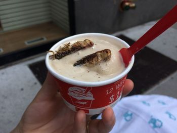 Cropped image of hand holding ice cream in disposable cup