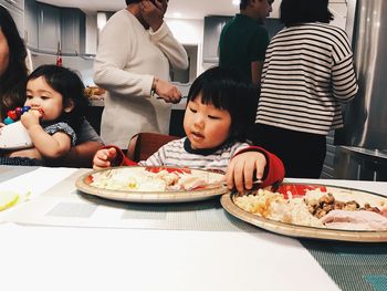 Father and daughter sitting on table at home