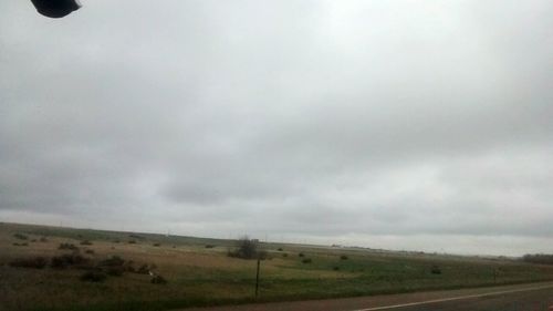 Scenic view of field against cloudy sky