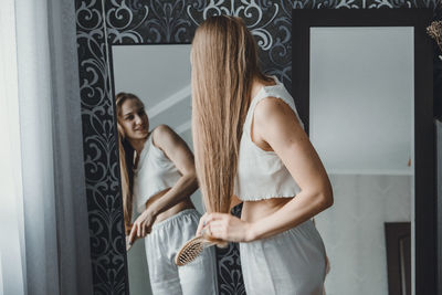 Young woman holding hair looking at mirror