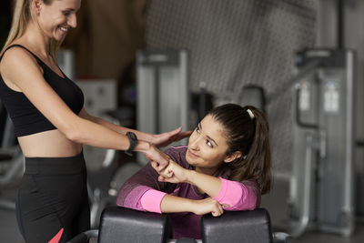 Instructor fist bumping with woman in gym