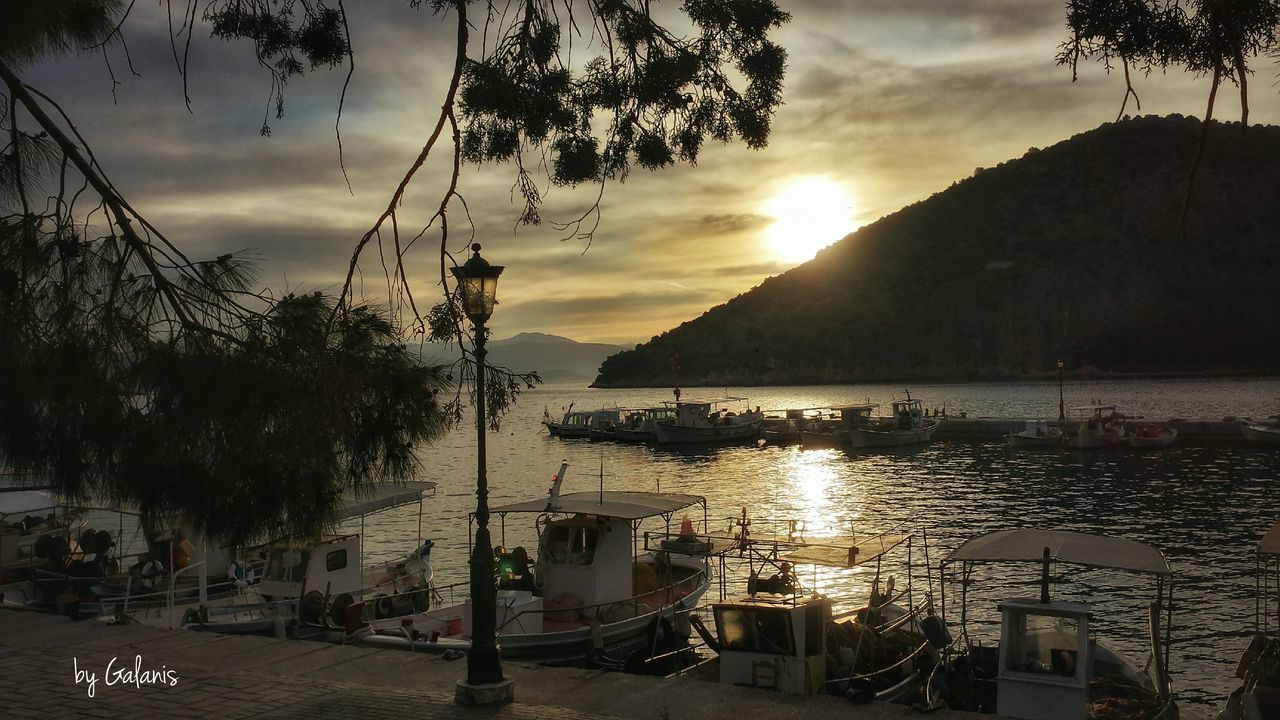 BOATS MOORED AT HARBOR AGAINST CLOUDY SKY