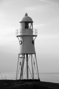 Lighthouse by sea against sky