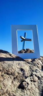 Low angle view of rocks against clear blue sky