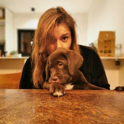 Portrait of woman with dog sitting at home