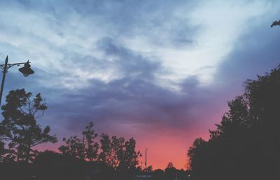 Low angle view of silhouette trees against dramatic sky