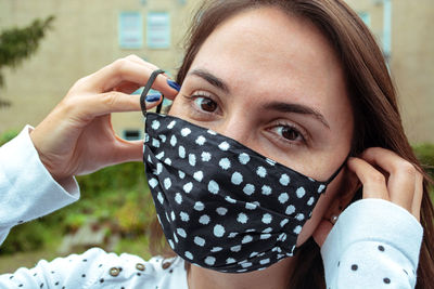 Portrait of smiling young woman holding camera outdoors