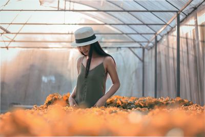 Full length of young woman standing in greenhouse