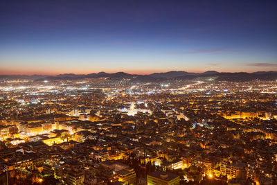 Aerial view of illuminated cityscape against sky at sunset