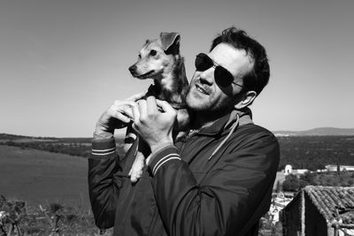 Man holding dog against sky