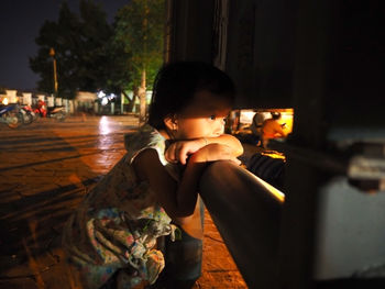 Rear view of boy looking at camera while sitting at night