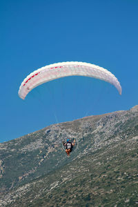 Person paragliding against clear blue sky