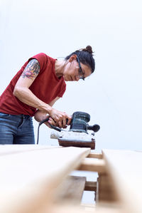 Young woman polishing a wooden plank with a power sander