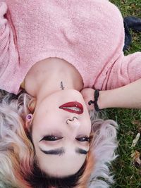 High angle portrait of smiling young woman lying on grassy field