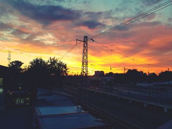 Silhouette electricity pylon against sky during sunset