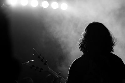 Rear view of man playing guitar at music concert