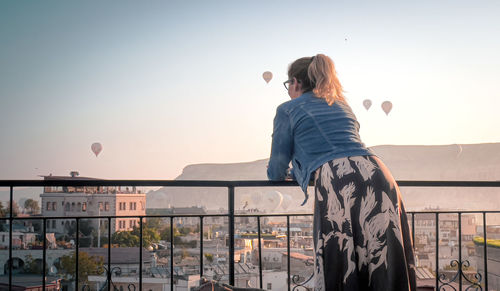 Rear view of woman standing against sky during sunset