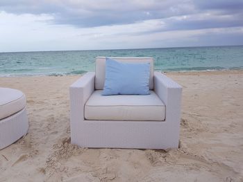 Chair on beach against sky