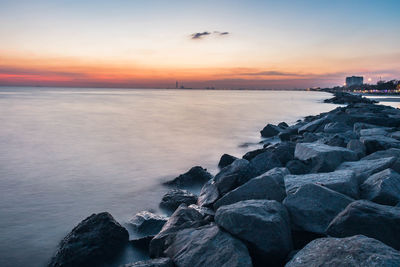 Rock formations at sea against sky during sunset