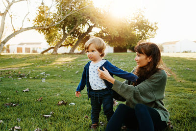 Happy mother and daughter on grass against plants