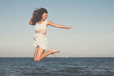 Woman jumping by sea