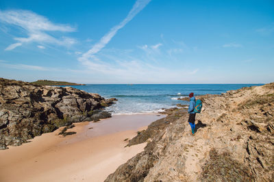 Rear view of woman walking at beach against sky