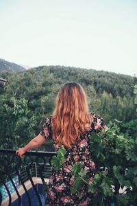 Rear view of woman looking at plants against sky