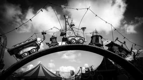 Low angle view of ferris wheel against cloudy sky