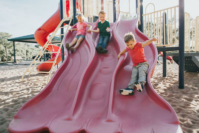 Playful children sliding in playground