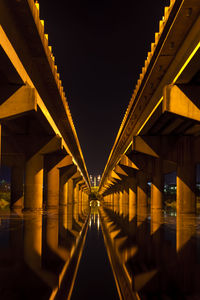 Illuminated bridge against sky at night