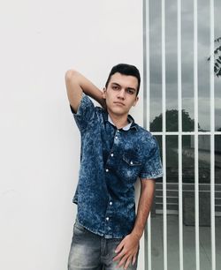 Portrait of teenage boy standing against building window