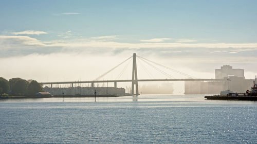 Bridge over river against cloudy sky