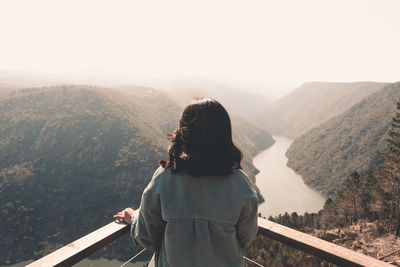 Rear view of woman looking at mountains against sky